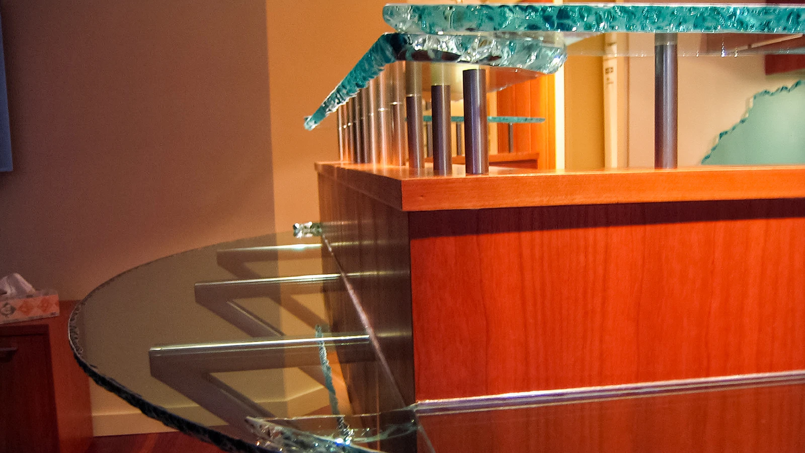 Layered glass bar top with metal supports and warm wood cabinetry